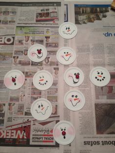 paper plates with snowmen painted on them sitting on top of a news paper page