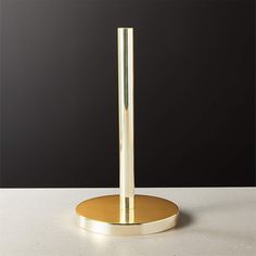 a gold plated table lamp on a white surface with a black wall in the background