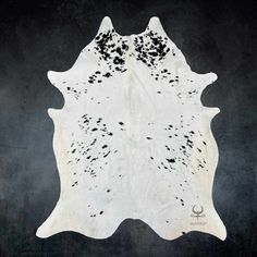 a black and white cowhide rug with spots on it's back side, in front of a dark background