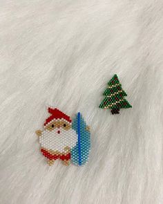 two beaded christmas trees and a santa clause ornament on a white fur surface