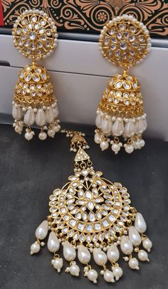 Beautiful Imitation Bridal Wedding Designer White Pearl Designer Earrings -Maang Tkka Set embedded with Semi-precious Stones like Pearl, glass, stones.  This product is Imitation & hence the product can be non-uniform & vary in color & texture. Color : White Gorgeous  Kundan Gold Plated Earrings-Tikka jewelry Set EXPEDITED DELIVERY (Chargeable) : Delivered 3 to 4 working days STANDARD DELIVERY (Free) : Delivered 8 to 10 working days Tikka Jewelry, Wedding Designer, Earrings Design, Wedding White, Gold Plated Earrings, Color Textures, White Pearl, Bridal Earrings, Bridal Wedding