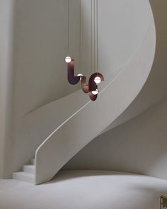 three circular lights hanging from the side of a spiral staircase in a room with white walls and flooring