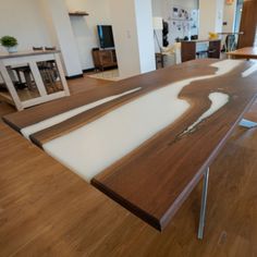 a wooden table with white paint on it in a living room and dining room area