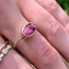 a woman's hand with two rings and a pink stone ring on her finger