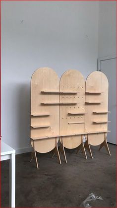 three wooden shelves sitting next to each other on top of a cement floor in front of a white wall