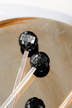 three black and white lollipops on a plate with sticks sticking out of them