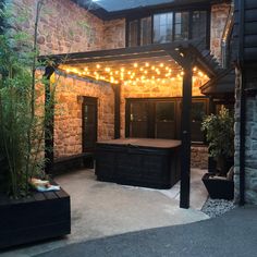 an outdoor hot tub under a pergolated patio with lights on the top and bottom