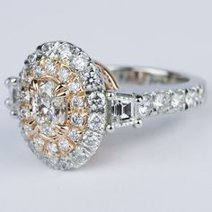 an engagement ring with two tone gold and white diamonds on the side, surrounded by smaller round brilliant cut diamonds