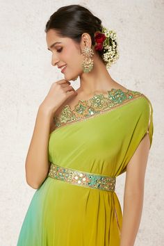 Editor's Note This one shoulder gown is stylish and comfortable, with drape and enhanced neckline that gives a feminine feel. It is combined with an embroidered belt on the waistline Fabric: Georgette Color: Green Component: Dress and belt Occasion: Festive Note: Product colour may slightly vary due to photographic lighting sources Care: Dry clean only About the Designer Gopi Vaid, co-founder of the eponymous label, is a designer with a passion for Indian arts and crafts. Raised in a family with Green Dress Combination Colour, One Shoulder Dress Indian, Fashion Course, Gopi Vaid, Dress And Belt, Blouse Yoke, Indian Arts, Indian Arts And Crafts, Lace Dress Design