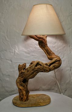 a table lamp made out of driftwood with a white shade on it's side