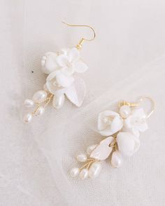 Gold and white ceramic floral bridal drop earrings. An elegant pair of gold wedding earrings. Ceramic flowers, dainty pearls and hand-painted leaves Your earrings come in a beautiful jewellery pouch for safe keeping. Feminine Flower-shaped Pearl Earrings For Weddings, Feminine White Flower Earrings With Pearl Drop, Feminine Pearl Flower Earrings For Weddings, Feminine White Pearl Flower Earrings, White Feminine Bridal Earrings, Feminine White Jewelry For Bridesmaid Gift, Delicate Pearl Earrings With Flower Charm For Wedding, Pearl Drop Flower Earrings For Wedding, Gold Handmade Flower Earrings For Wedding