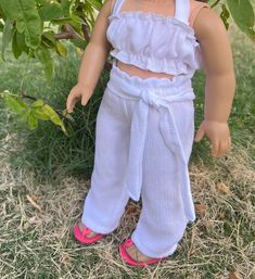 a doll is standing in the grass next to a tree