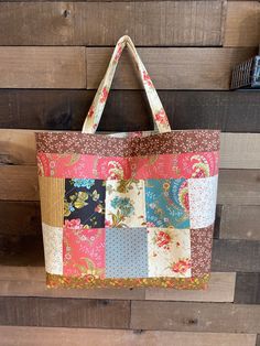 a multicolored patchwork tote bag hanging on a wooden wall