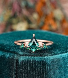 an emerald colored ring sitting on top of a velvet box