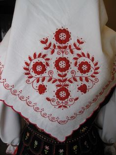 a woman's blouse with red flowers and leaves on the front, embroidered in white