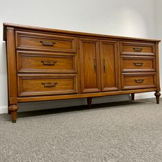 a large wooden dresser sitting on top of a carpeted floor next to a wall