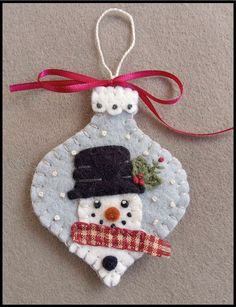 a snowman ornament hanging from a red ribbon