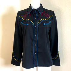 Scully Western Embroidered Shirt In Medium Black Shirt Red, Blue & Yellow Embroidery Pearl Snap Front & Cuffs Embroidered Horses & Other Detail Blue Ping Trim Long Sleeves Condition, Never Worn Medium Measures About Armpit 20 12” Length 24” Ships Same Day Smoke Free Pet Free Tag, Western Cowgirl Cowboy Equestrian Roper Ariat Embroidered Button-up Western Tops, Western Style Embroidered Button-up Top, Black Embroidered Western Top, Black Top For Spring Rodeo, Black Button-up Top For Rodeo, Embroidered Fitted Shirt For Fall, Fitted Embroidered Shirt For Fall, Western Long Sleeve Top With Floral Embroidery, Fitted Embroidered Top For Rodeo