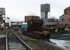 an abandoned train yard with buildings in the background