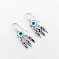 Add a touch of protection and style with our Evil Eye Feathers Earring. Made with sterling silver, these dangle earrings are an elegant addition to any outfit. The hook ear wire style ensures comfortable wear, while the striking evil eye in the middle adds a unique touch. Stay stylish and secure with these earrings. Feather Earrings, The Hook, Ear Wire, Evil Eye, Feathers, Dangle Earrings, Sterling Silver, Silver