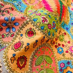 close up view of colorful fabric with gold beading and flower designs on it's edges