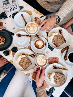 people sitting at a table with plates of food and cups of coffee in front of them