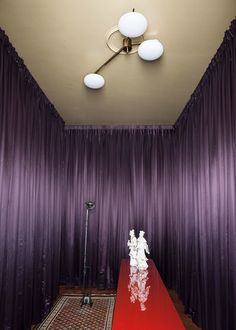 a room with purple curtains and a red table in front of the curtained wall