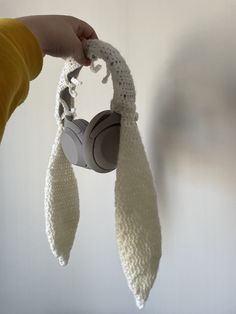 a person is holding up a crocheted headphone holder in the shape of a scarf