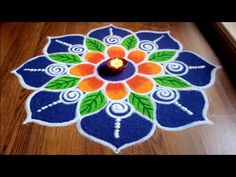 a blue and orange flower design with a candle in the center on a wooden floor