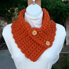 an orange crocheted cowl with buttons on it's collar is shown