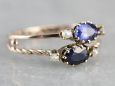 "Two bands, one twisted, one simple and polished have been fused together to create this ready-made stacking set, with oval cut sapphires, one a shade darker than the other, both accented perfectly by creamy white seed pearls, this ring is wonderfully crafted, unique and super sweet! Metal: 10K Yellow Gold Gem: 2 Sapphires totaling 1.11 Carats Gem Measurements: 6 x 4 mm, Oval Accents: 4 Seed Pearls Ring Size: 8.25 Marks: \"10K\" Stamped on the inside band SKU #: U52URV7Y Each piece has been iden Elegant Oval Multi-stone Stackable Rings, Multi-stone Stackable Rings, Formal Oval Sapphire Stackable Ring, Oval Jewelry With A Modern Twist For Weddings, Modern Twist Oval Wedding Jewelry, Classic Oval Stackable Sapphire Ring, Classic Oval Sapphire Stackable Ring, Anniversary Sapphire Stackable Rings In Oval Shape, Anniversary Sapphire Stackable Rings With Oval Shape