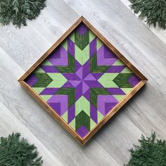 a wooden frame with an abstract design in the center and pine needles on the bottom