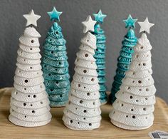 three small ceramic christmas trees on a wooden table next to each other with white stars