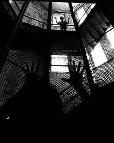 the silhouettes of people standing in an enclosed area with their hands up and arms out