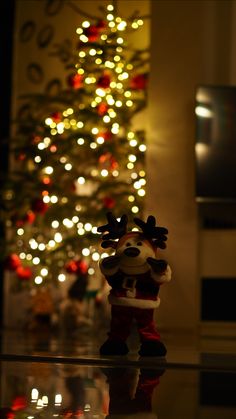 a christmas tree with lights in the background and a toy santa clause standing next to it