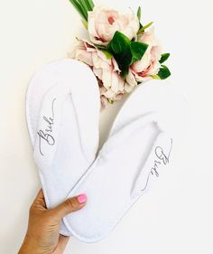 two white slippers with the word love written on them next to a bouquet of flowers