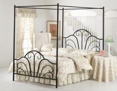 a bedroom with a white bed and black iron frame headboard, night stand and nightstand