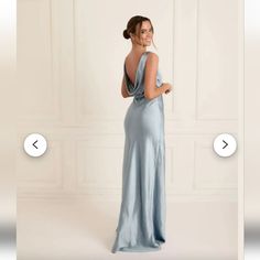 a woman in a long blue dress is looking at the back of her dress and smiling