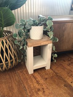 a white planter sitting on top of a wooden table next to a potted plant