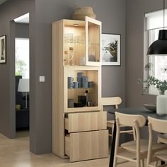 a wooden cabinet with glass doors in a dining room next to a table and chairs