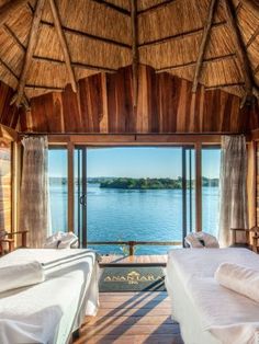 two beds in a room with wooden walls and windows overlooking the water on both sides