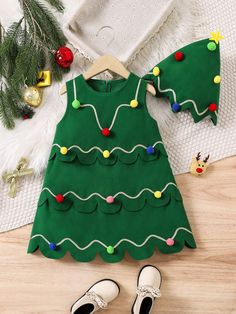 a green christmas tree dress with shoes on the floor next to it and other holiday decorations