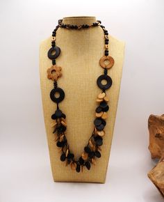 Enhance your jewelry collection with this beachy Vintage Carved Black & Tan Wood or Composite Multi Strand Flapper Necklace.  The necklace features a layered and beaded design of knotted string with a length of 44 inches, making it perfect to gift or wear on special occasions like Mother's Day, Christmas, or Birthday.  This handmade necklace is a true bohemian beauty, with its black, brown, tan and beige circular discs, donut circles, a flower, and ethnic theme, and  it is sure to complement many outfits.     This necklace is a unique piece is not signed and with an unknown country of origin.  Excellent vintage condition and ready to wear. Drop length:  22 Inches Bohemian Beauty, Flapper Necklace, Beignets, Handmade Necklace, Last Minute Gifts, Multi Strand, Black Tan, Black And Tan, Statement Jewelry