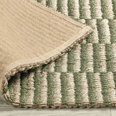 a close up of a rug on the floor with a white and green stripe pattern