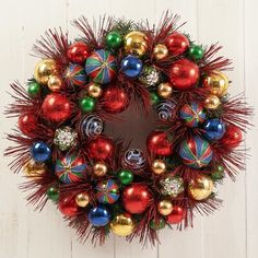 a christmas wreath with red, green and gold ornaments hanging from it's center