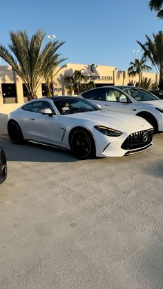 three cars parked in a parking lot next to palm trees