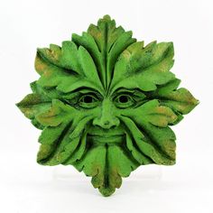 a green mask with leaves on it's face is shown in front of a white background