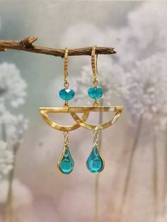 Lovely luxury pair of statement earrings consisting of a half-moon geometrical shape, a blue glass bead, and the statement piece which is a three times KC gold plated shiny Zircon crystal charm in the shape of a water drop. The earring hooks are also gold plated for that luxurious feel when worn.  The earrings are packaged in a elegant gift pouch prior to sending which will make this pair the ideal present whether it's for yourself or a loved one.  Thank you for visiting my shop! Elegant Turquoise Metal Chandelier Earrings, Teardrop Earrings Gold, Crystal Teardrop Earrings, Earrings Crystal, Gift Pouch, Crystal Charm, Earring Hooks, Water Drop, Elegant Gift