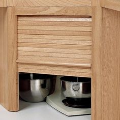 a close up of a kitchen counter with pots and pans under the cabinet door