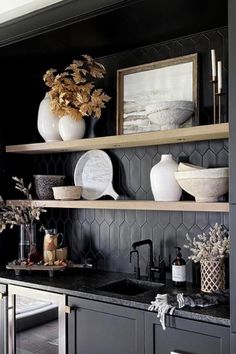 a kitchen with black cabinets and white vases